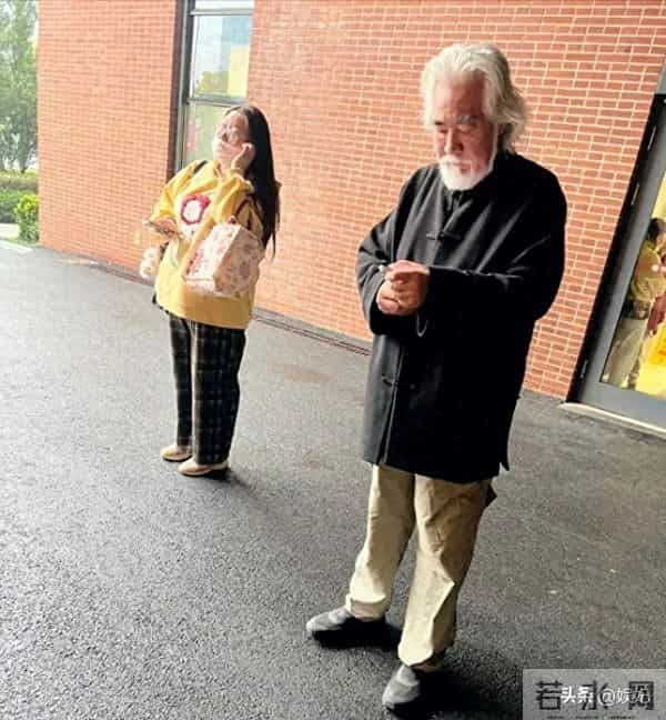 75岁张纪中现身浙江医院急诊门口，他站着看手机，表情凝重。