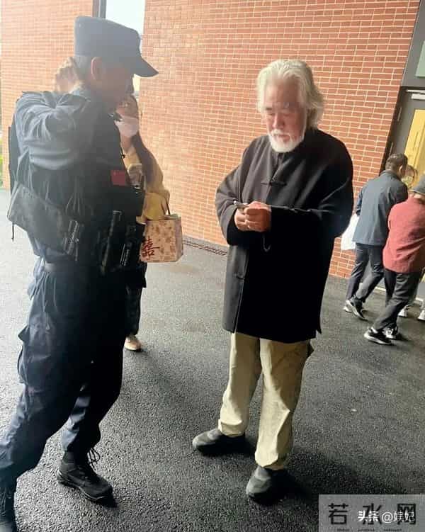 75岁张纪中现身浙江医院急诊门口,他站着看手机,表情凝重。