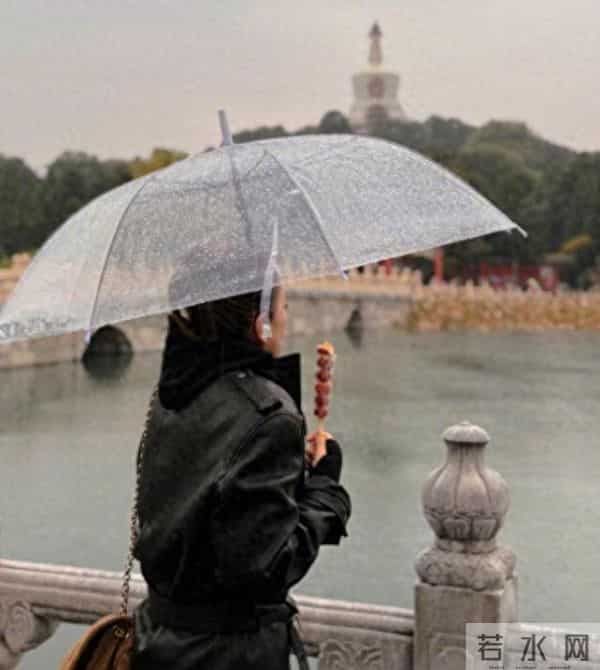59岁巩俐现身北京公园，穿黑皮衣配透明伞，雨中喝酸奶吃冰糖葫芦