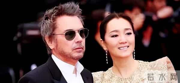 59岁巩俐现身北京公园，穿黑皮衣配透明伞，雨中喝酸奶吃冰糖葫芦