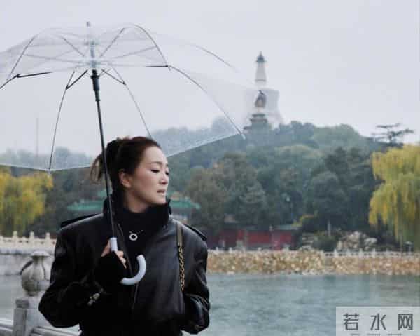 59岁巩俐现身北京公园，穿黑皮衣配透明伞，雨中喝酸奶吃冰糖葫芦