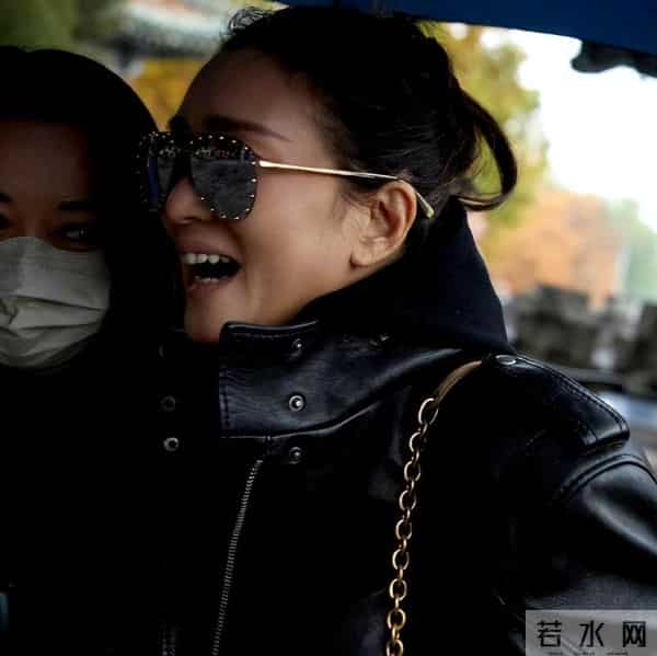 59岁巩俐现身北京公园，穿黑皮衣配透明伞，雨中喝酸奶吃冰糖葫芦