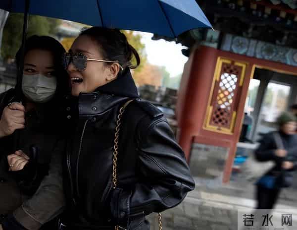 59岁巩俐现身北京公园，穿黑皮衣配透明伞，雨中喝酸奶吃冰糖葫芦