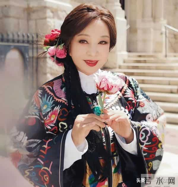 刘晓庆真的不服老啊，身穿黑色花纹袍子，头上别着几朵鲜花