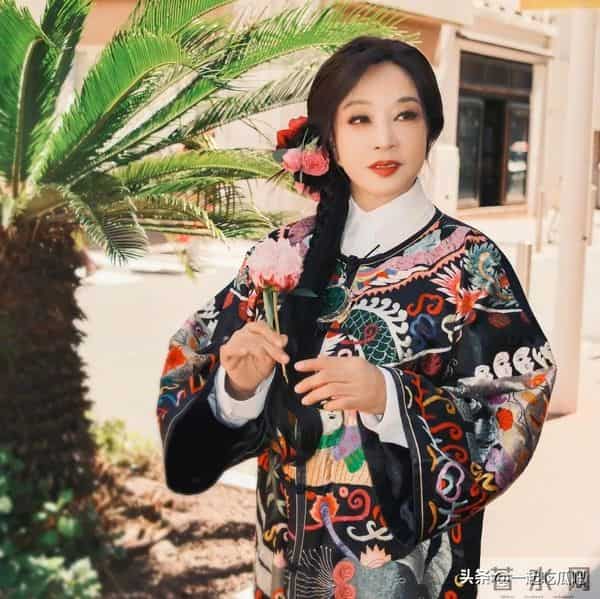 刘晓庆真的不服老啊，身穿黑色花纹袍子，头上别着几朵鲜花